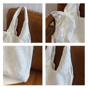 Close-up of white lace floral embroidery and large bow detail on the tote bag