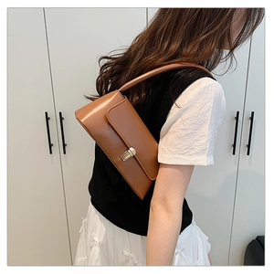 Sac baguette marron vintage avec boucle dorée porté à l'épaule pour un look d'été