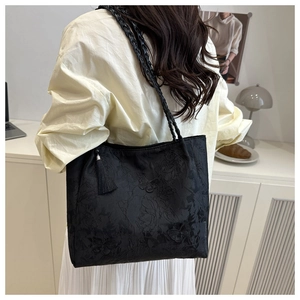 Détail du sac cabas en jacquard noir avec broderie papillon et pompon à franges élégant