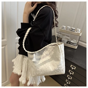 Détail de la broderie florale en dentelle blanche sur sac cabas avec pompon décoratif
