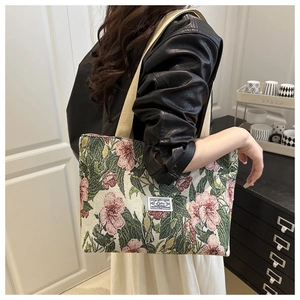 Detail view of floral tapestry canvas tote bag with woven handles and brand label