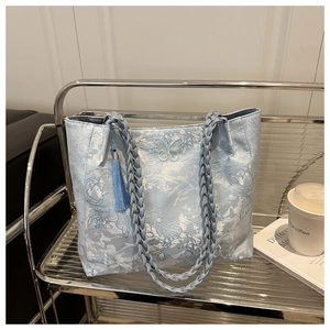 Detail of light blue tote bag with butterfly jacquard and woven handles