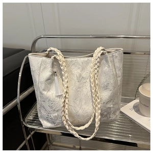Detail of floral lace embroidery and butterfly pattern on off-white tote bag