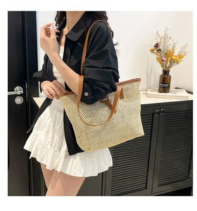 Détail du grand sac cabas en paille tissée avec anses en cuir marron porté par mannequin