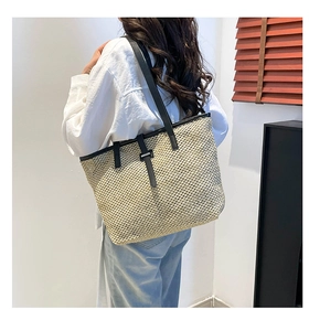 Détail d'un grand sac cabas en paille avec bandoulières en cuir noir pour vacances