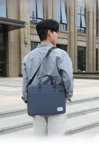 Man carrying a dark blue slim laptop bag with handle and adjustable shoulder strap outdoors