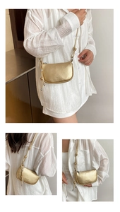 Dettaglio borsa in pelle dorata con trama litchi, nodo decorativo e ciondolo a M