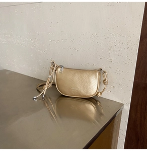 Dettaglio borsa a sella color champagne con texture litchi e manico con nodo chic