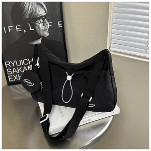 Detail der schwarzen Nylon-Tasche mit Faltendesign, Rundbeutel und verstellbarem Gurt