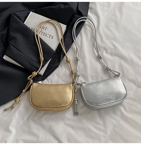 Dettaglio di borse in pelle con trama litchi in oro e argento e tracolle con nodi eleganti