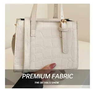 Detail showing the cream crocodile embossed texture and hardware on this handbag
