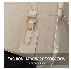 Detail of cream faux crocodile leather handbag with gold hardware and stylish charm