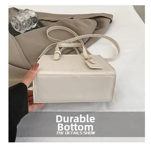Close-up of the wear-resistant rectangular base on a cream crocodile-embossed handbag