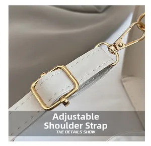 Detail of adjustable white leather handbag strap with polished gold-tone metal hardware