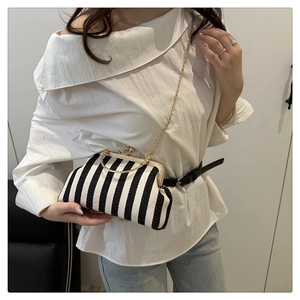 Chic black and white striped handbag with golden frame clasp worn with casual white outfit