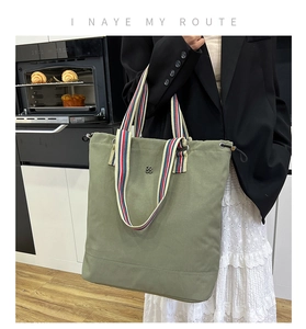 Close-up of sage green canvas bucket bag with tri-color striped handles and floral logo