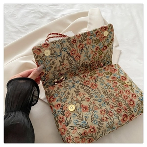 Detail of floral tapestry handbag with dual gold magnetic clasps and red chain strap