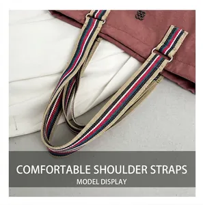 Detail of canvas shoulder bag with colorful striped strap and clover metal ornament