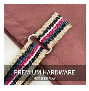 Close-up of pink shoulder bag with striped woven strap and silver metal D-ring attachment