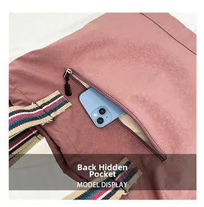 Macro view of a back anti-theft zipper pocket on a mauve nylon crossbody bag for students