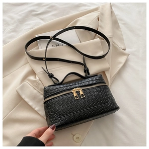 Detail of black box crossbody bag with woven texture and gold dual zippers on suit jacket