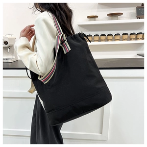 Detail of black canvas tote bag with red, white and blue woven striped shoulder straps