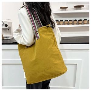Detailed back view of a yellow canvas tote bag with tri-color striped shoulder strap
