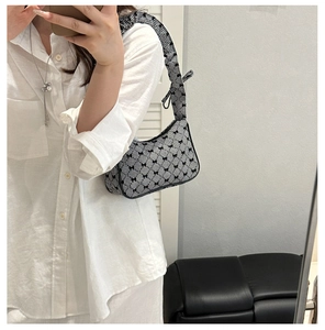 Close-up of black and white checkered handbag featuring delicate bow embroidery and ruffled strap