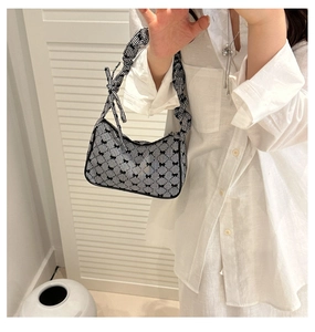 Detail of checkered shoulder bag with black bow prints and a scrunchie handle strap