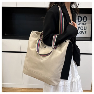 Detail of beige canvas tote bag with striped straps and flower embroidery texture