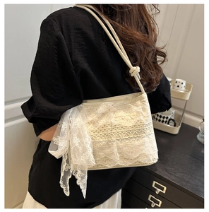 Side view of cream lace bucket bag featuring intricate ruffles and a large bow detail