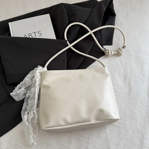 Detail of cream leather tote bag with elegant white floral lace ribbon and silver hardware