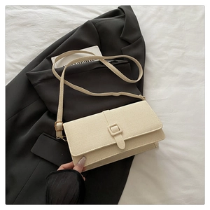 Detailed view of cream woven texture and golden buckle on retro crossbody shoulder bag