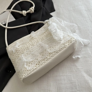 Detailed close-up of ivory lace embroidery and ruffled layers on a shoulder tote bag