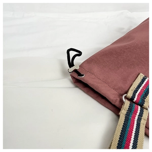 Macro shot of silver drawstring buckle and colorful woven shoulder strap on the bag