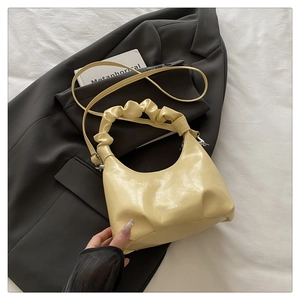 Detail of light yellow ruched handle bag on a grey blazer for modern fashion aesthetic