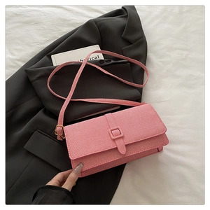 Detail of pink crossbody bag featuring diagonal weave texture and square buckle flap
