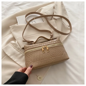Close-up of woven texture and gold dual zipper on tan crossbody bag with top handle