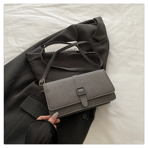 Detail of grey rectangular crossbody bag with diagonal twill texture on a grey suit