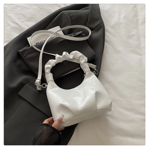 Close-up of a white pleated dumpling bag with cloud handle and silver fashion lettering