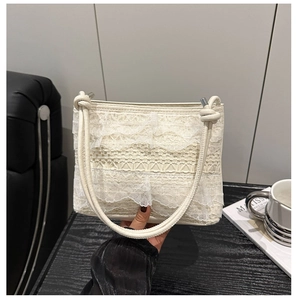 Detail of cream lace shoulder bag with ruffled layers and knotted leather strap handle