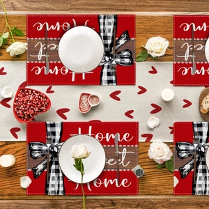 Gros plan de sets de table rouges Home Sweet Home avec nœuds vichy sur table en bois