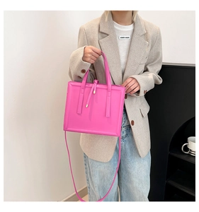 Detailed view of a bright pink square shoulder bag featuring a modern minimalist design