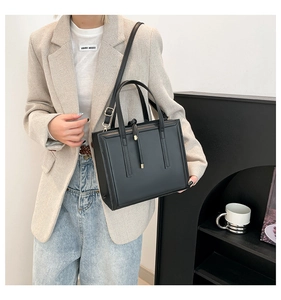 Detail view of a black leather rectangular crossbody bag with vertical embossed lines