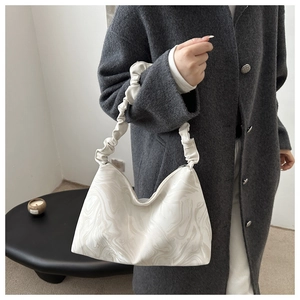 Détail du sac cabas blanc à motif marbré avec poignée froncée sur manteau en laine