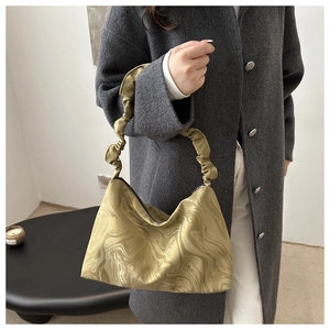 Détail du sac satiné vert marbré avec anse plissée porté sur un manteau en laine grise