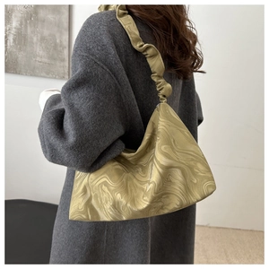 Detail of marble pattern shoulder bag with ruffle strap on a model wearing an overcoat