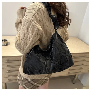 Détail du sac hobo noir brillant avec texture marbrée et bandoulière plissée