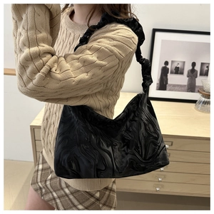 Close-up of black crossbody bag with marble texture and trendy ruched cloud shoulder strap