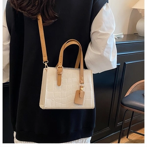 Detail of cream crocodile embossed leather tote bag with brown straps and gold buckle
